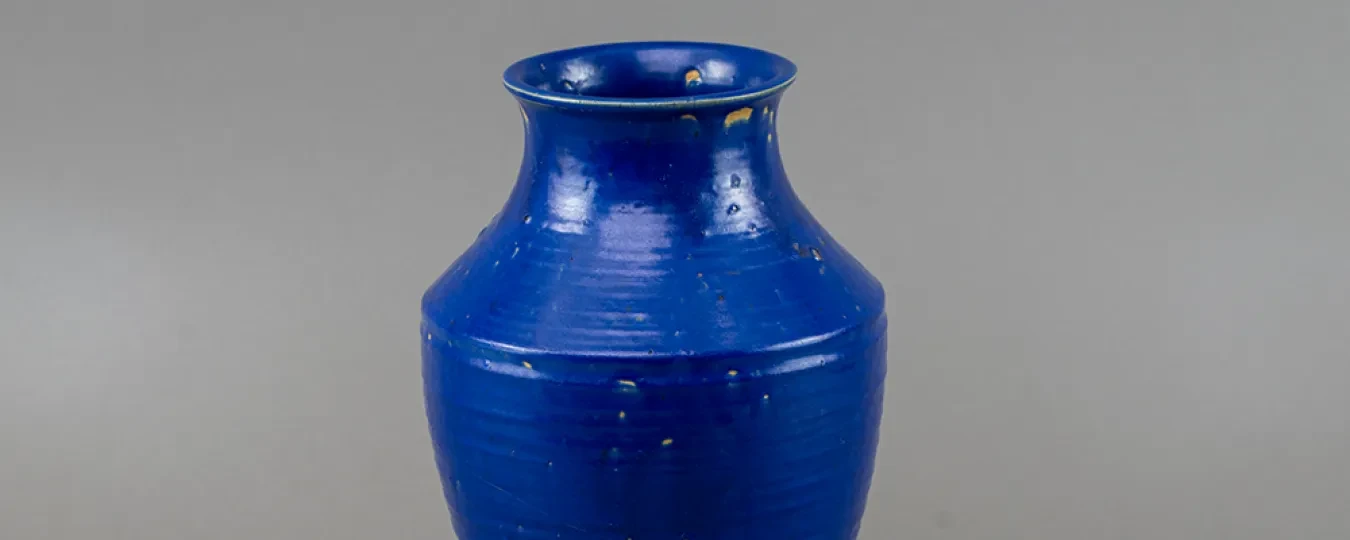 Blue ceramic vase with a glossy finish, on a gray background.