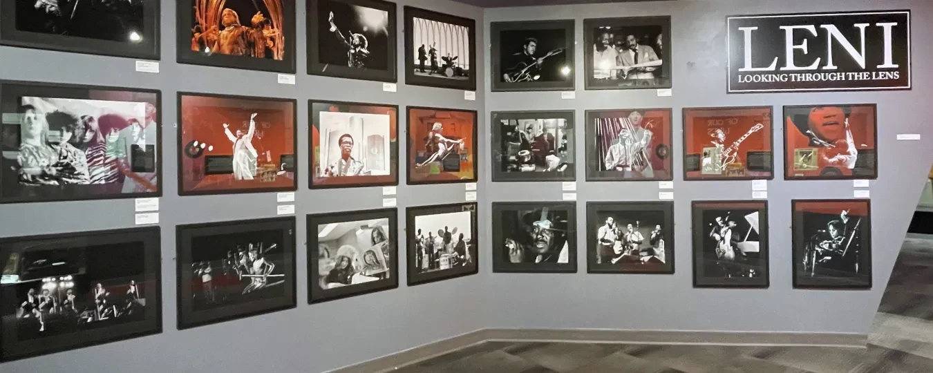 Wall displaying black-and-white and color concert photographs arranged in a gallery setting.