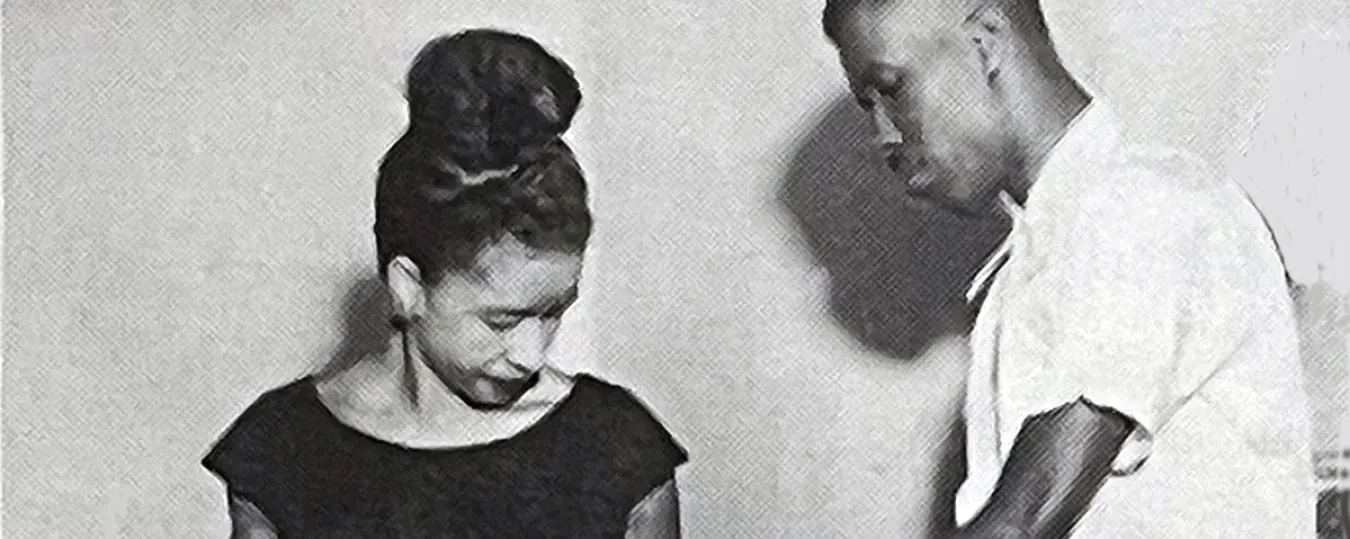 A man offers assistance to a woman wearing a polka dot skirt.