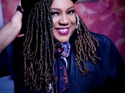 A smiling woman in a top hat.