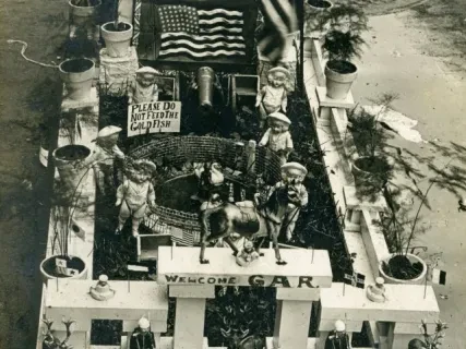 A miniature park display with statues, plants, and flags, labeled "Smallest Park in the World, Detroit."