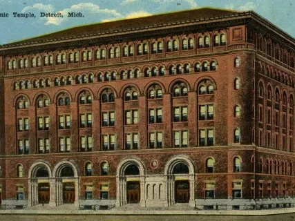Historical brick building with arched windows and detailed facade, set against a blue sky.