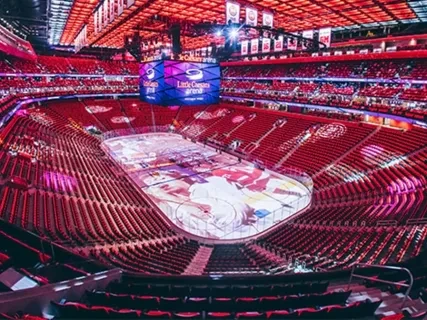 Colorful hockey arena with red seats and illuminated ice rink under vibrant lights.