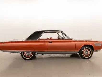 Classic orange car with a black roof in a studio setting.