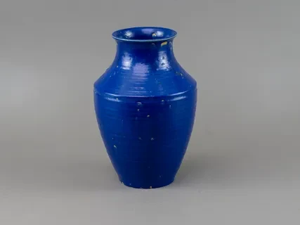 Blue ceramic vase with a glossy finish, on a gray background.
