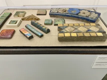 Decorative ceramic tiles and borders displayed in a glass case.