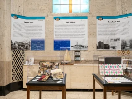 Exhibit room with historical posters on walls, small ship model, and assorted memorabilia on tables.