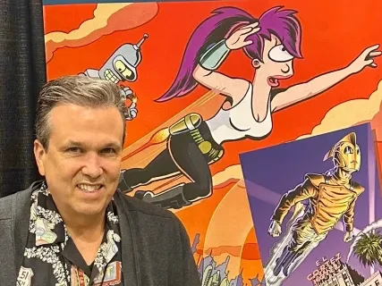Man smiling in front of colorful cartoon poster with futuristic characters.