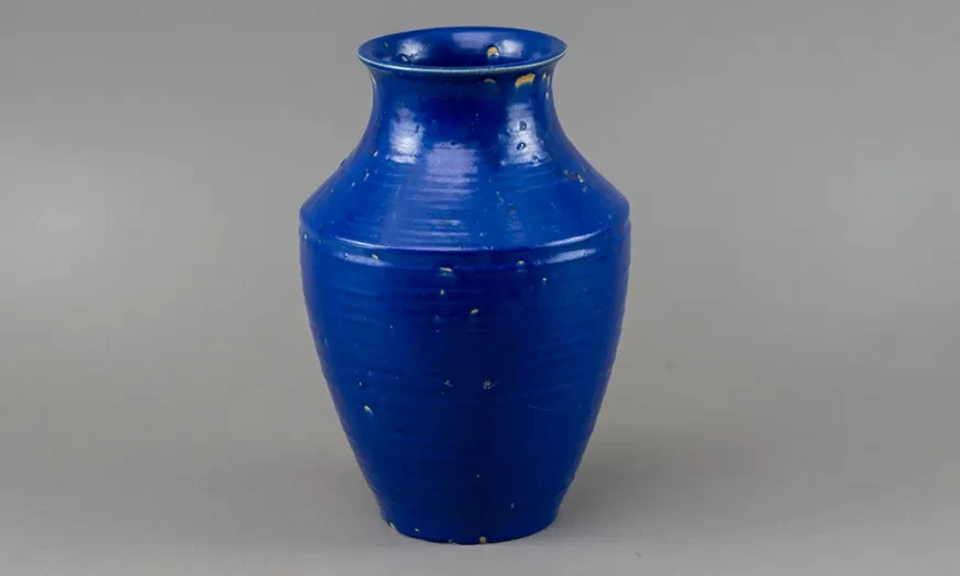 Blue ceramic vase with a glossy finish, on a gray background.