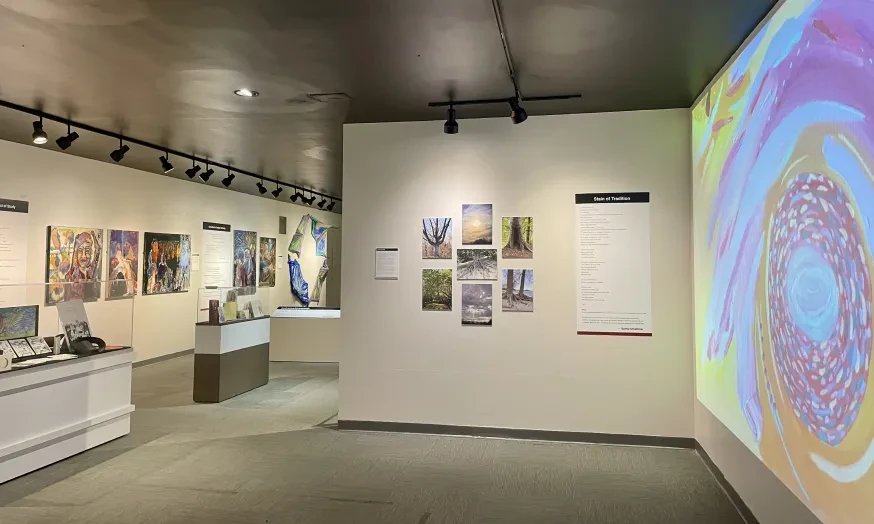 Art gallery interior with colorful paintings, a large abstract display on the right, and soft overhead lighting.