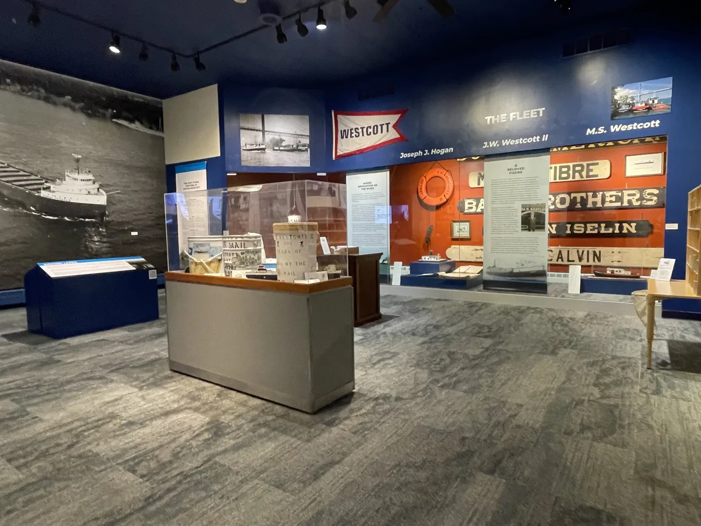 Exhibit room with historical displays, glass cases, and large wall photos in a maritime-themed museum setting.