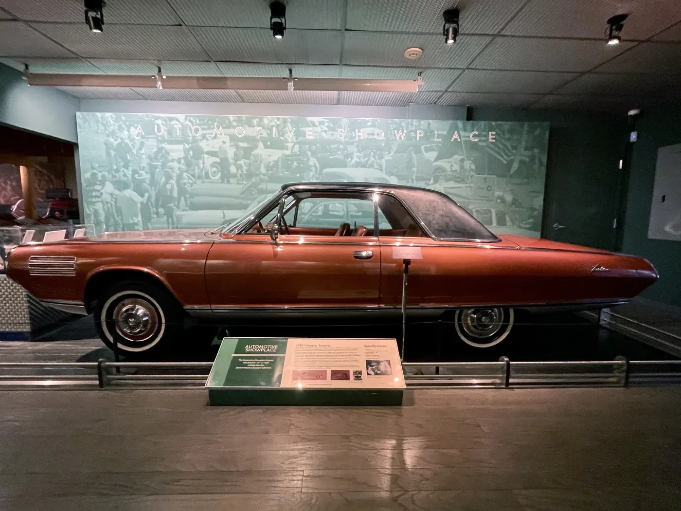Red vintage car displayed in a museum exhibit setting.