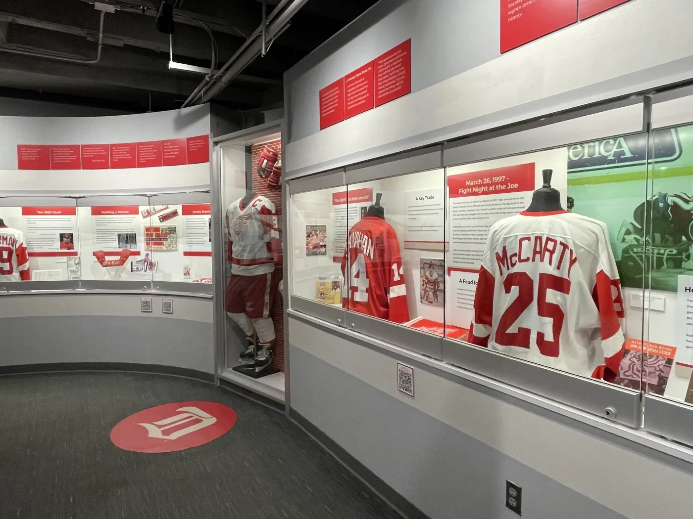 Hockey exhibition with jerseys, including a large display of McCarty's number 25 jersey, in a glass case.