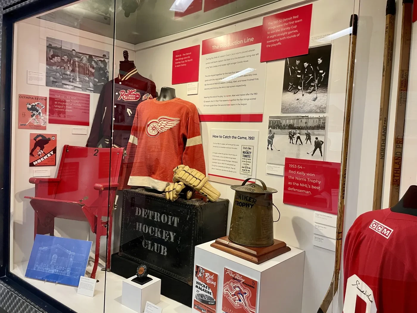 Sports memorabilia display with vintage jerseys, hockey sticks, and historical photos.