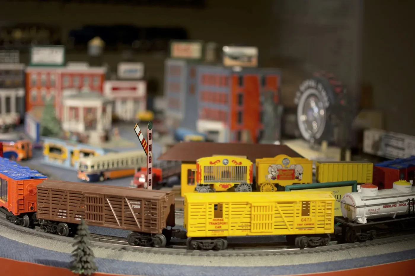 Model train set with colorful trains, buildings, and a ferris wheel on a circular track.