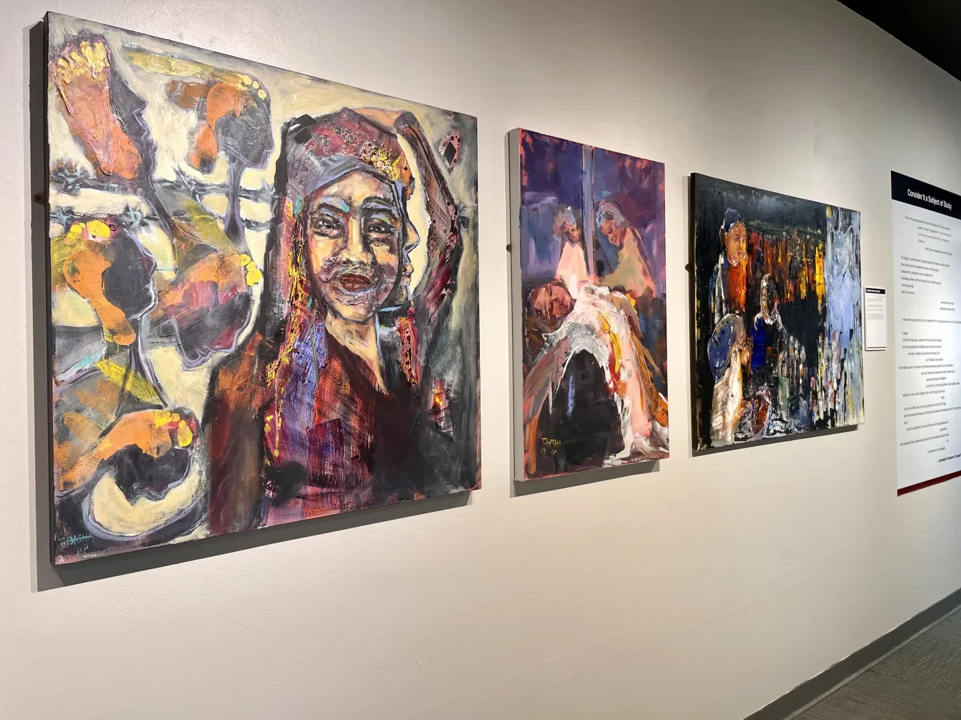 Three colorful abstract paintings hang on a gallery wall.