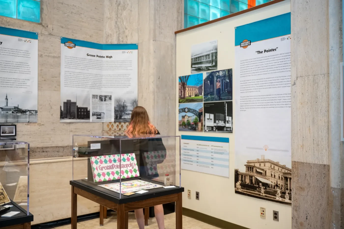 Exhibit room with posters, a display case, and a woman observing.