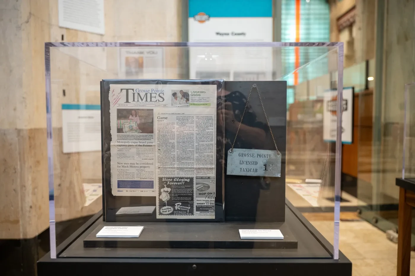 Newspaper exhibit inside a glass case, displayed in a museum setting with informational panels in the background.