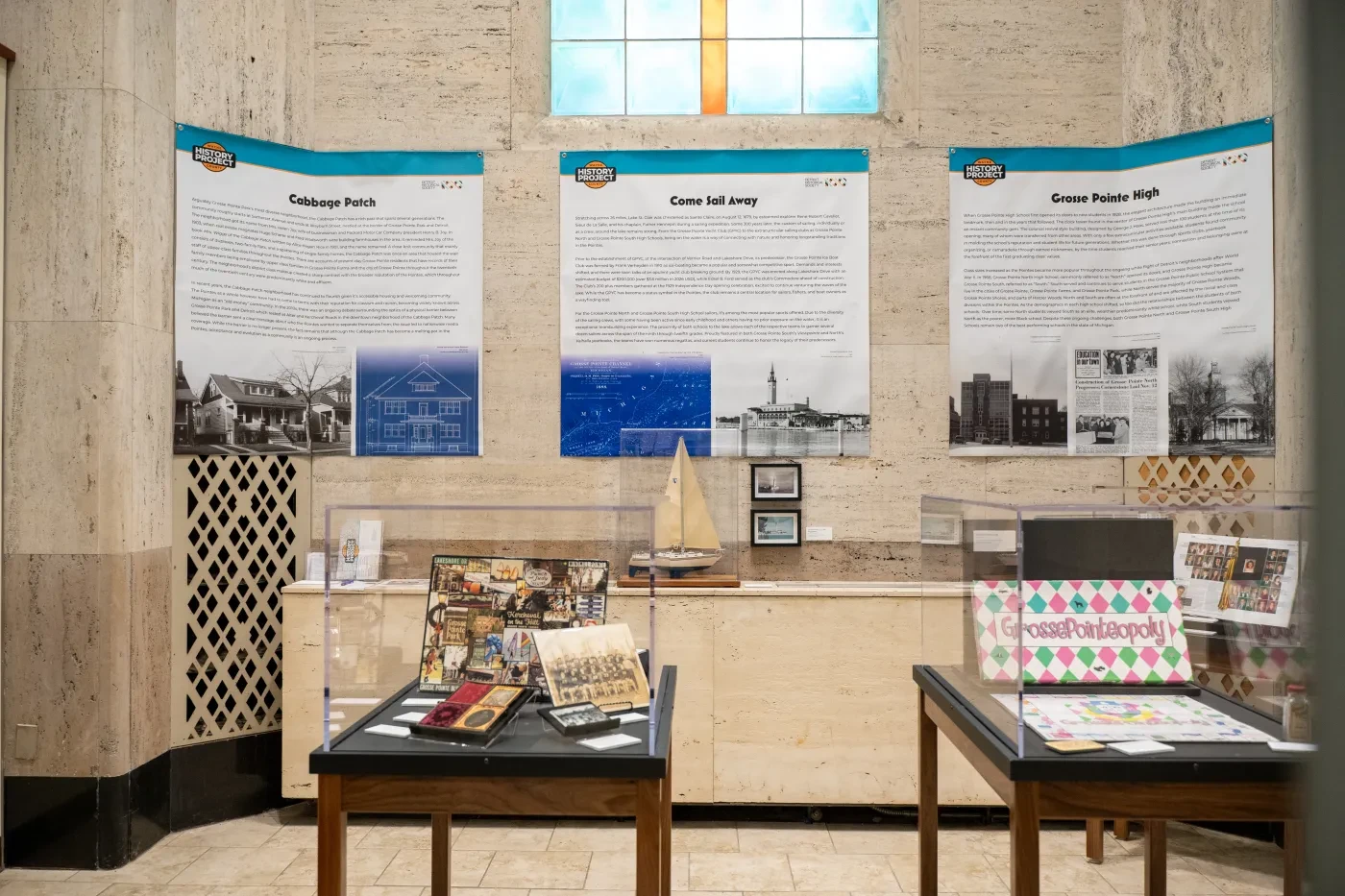 Exhibit room with historical posters on walls, small ship model, and assorted memorabilia on tables.
