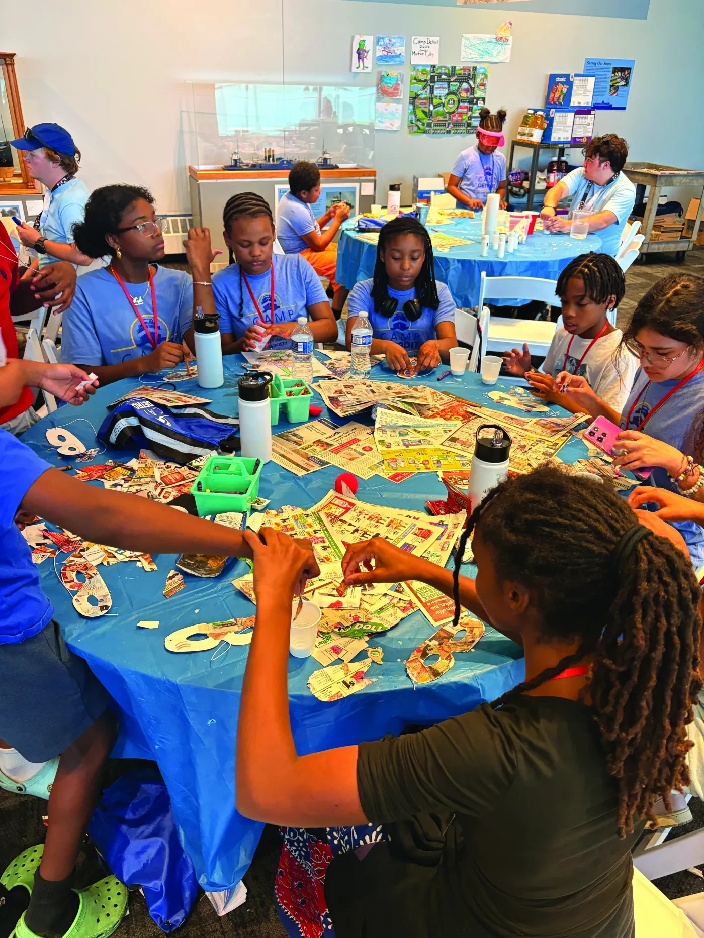 Children sitting around a table engaged in a craft activity with colorful paper and markers.