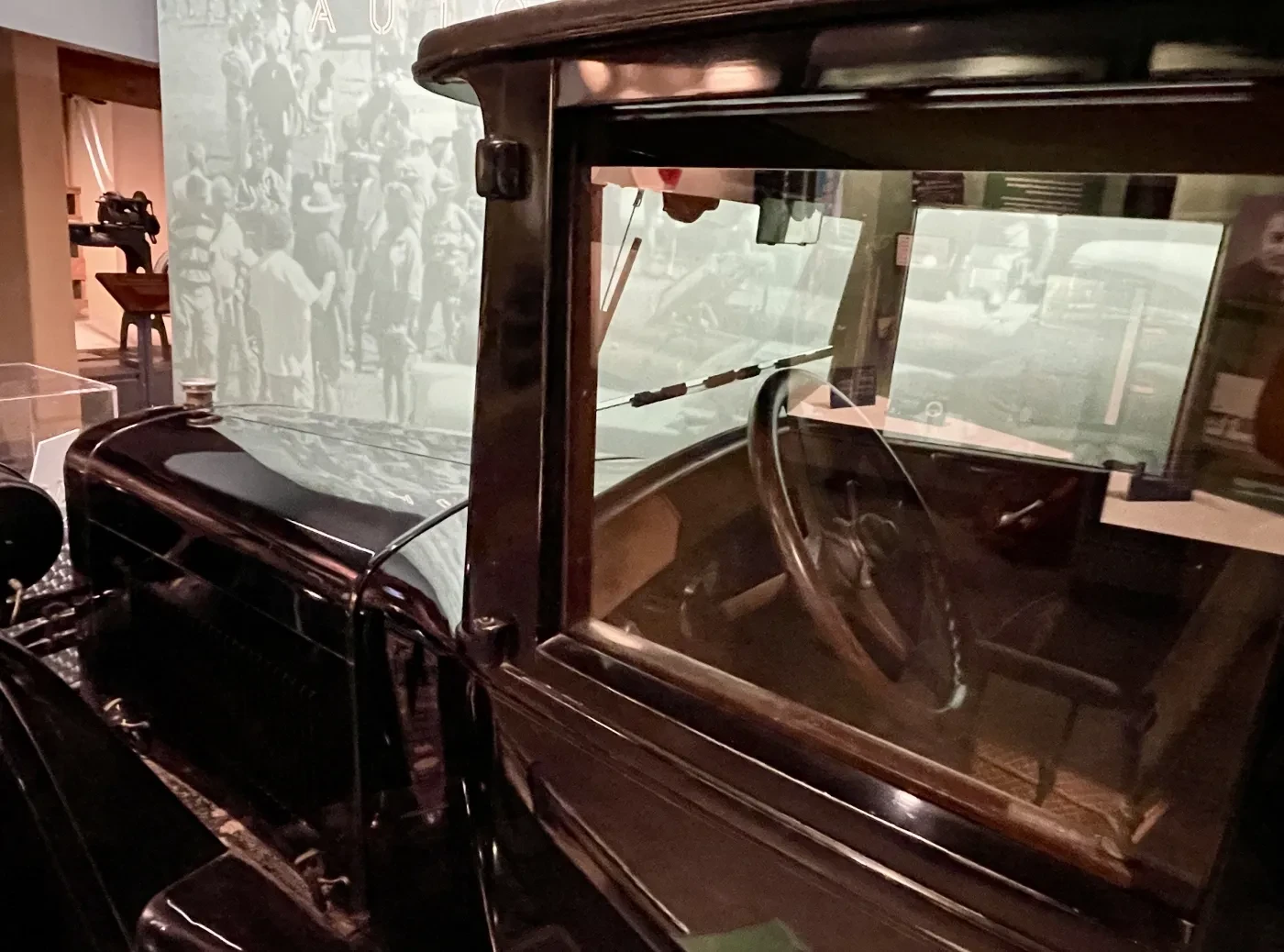 Vintage car interior with steering wheel and dashboard in a museum setting.