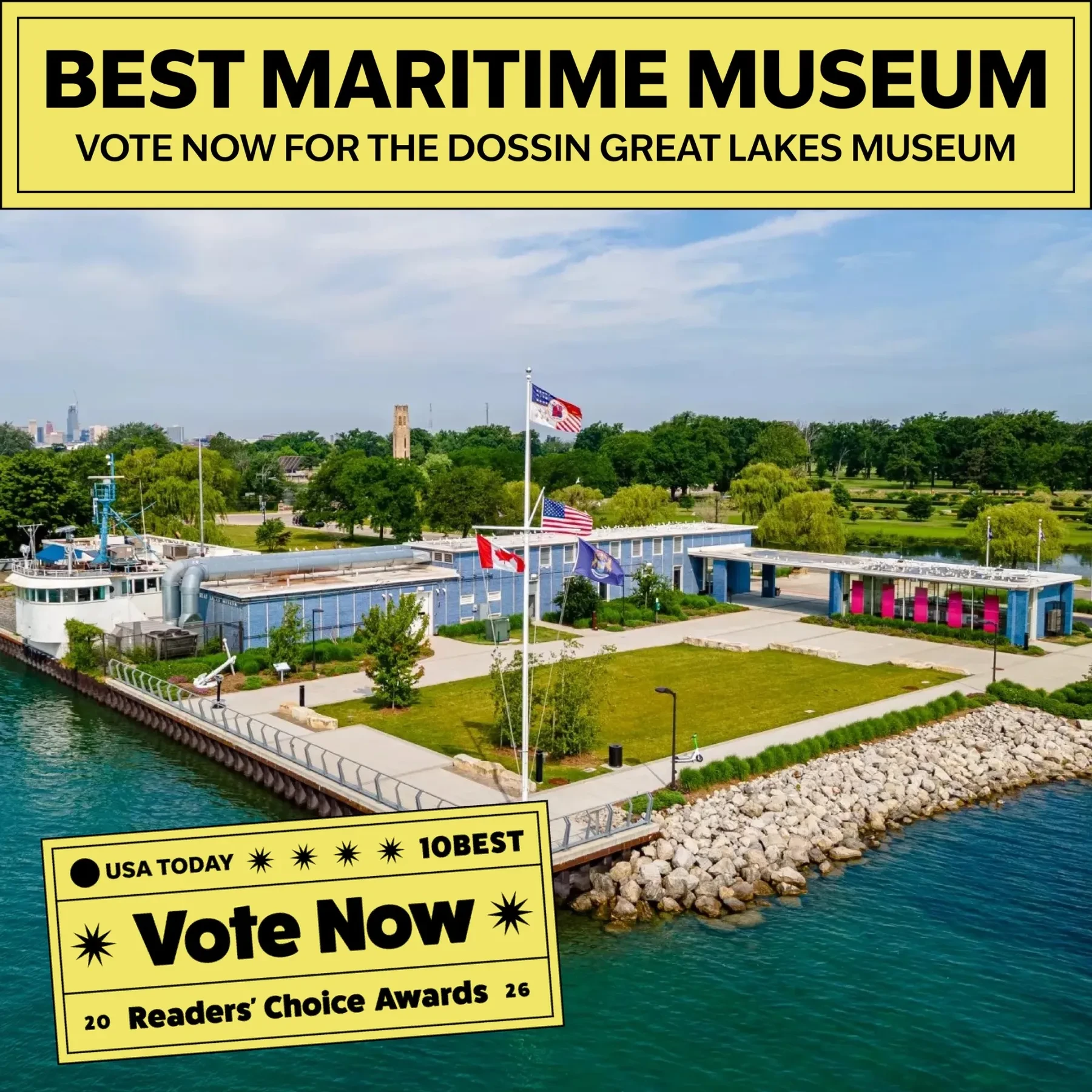 Dossin Great Lakes Museum by the waterfront, surrounded by greenery and flags, under a blue sky.